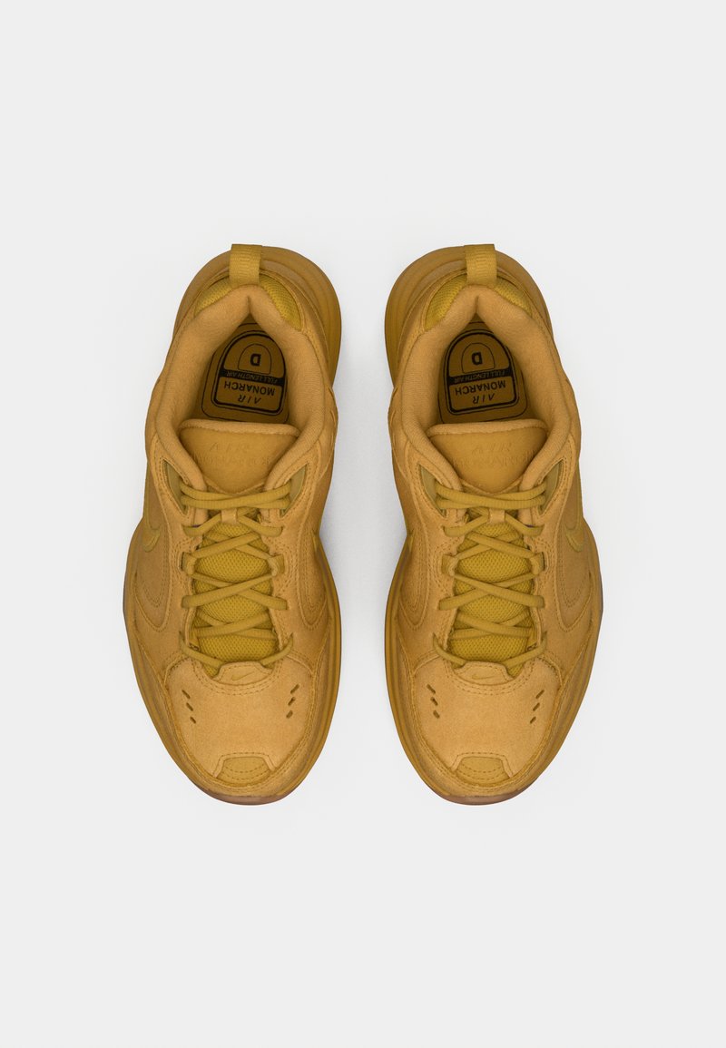 Un par de zapatillas Nike Air Monarch en color marrón con cordones, vistas desde arriba sobre un fondo blanco.