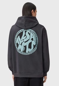 Felpa con cappuccio grigio scuro con una grande grafica circolare verde menta e testo stilizzato sul retro. Tessuto morbido con cappuccio regolabile tramite coulisse.