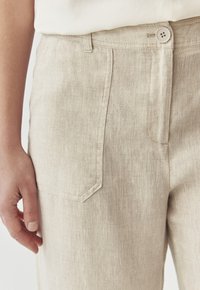 Lichtbeige linnen broek met een gladde textuur, voorzien van een voorzak, subtiele stiksels en een knoopsluiting bij de taille.