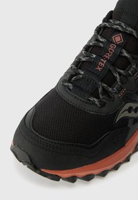 Czarne buty sportowe wykonane z siateczki i materiału syntetycznego, z fakturowaną powierzchnią i pomarańczowymi akcentami. Zawierają odblaskowe sznurowadła i logo.