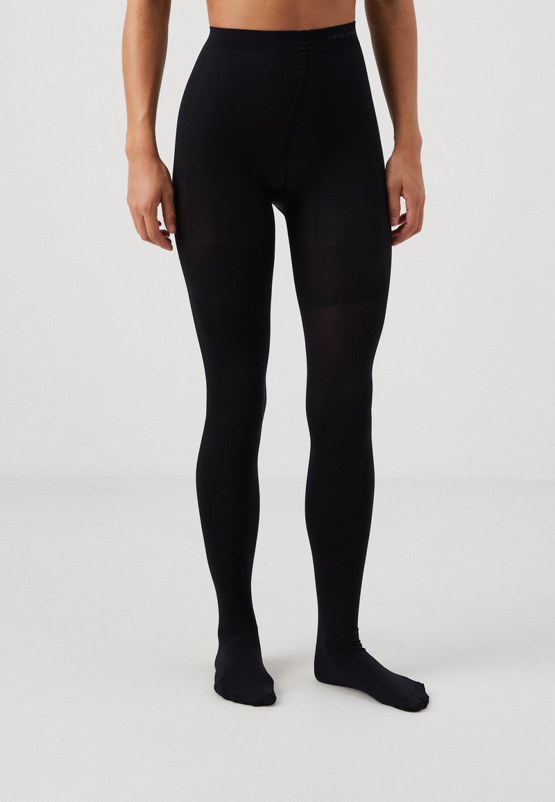 Černé legíny s vysokým pasem, vyrobené z hladkého, elastického materiálu. Disponují bezešvou konstrukcí a stylovými nohavicemi.