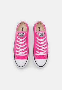 Baskets en toile rose avec lacets blancs, embout en caoutchouc et accents noirs. Présentent le logo Converse sur la languette et les côtés.