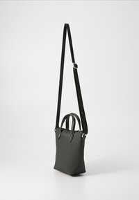 Sac fourre-tout noir texturé avec deux poignées supérieures et une bandoulière amovible et ajustable. Equipé de matériel en métal argenté et d'une fermeture éclair.