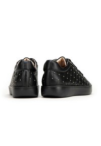 Black quilted sneakers with a smooth texture, featuring gold studs, a rounded toe, and a contrasting black sole. Rear view shown.