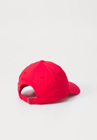 Piros vászon baseball sapka ívelt virágzattal, hátul állítható pánttal és hat panelből álló kivitelben, középen egy gombbal.