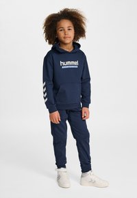 Completo felpa con cappuccio e pantaloni della tuta blu navy, realizzato in tessuto morbido, con tasca frontale, stampa del logo e dettagli a righe sulle maniche.