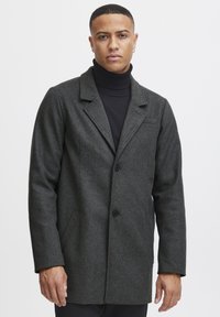 Abrigo de mezcla de lana gris oscuro con cuello con muescas, dos botones y bolsillos laterales. Textura suave, corte ajustado y diseño minimalista.