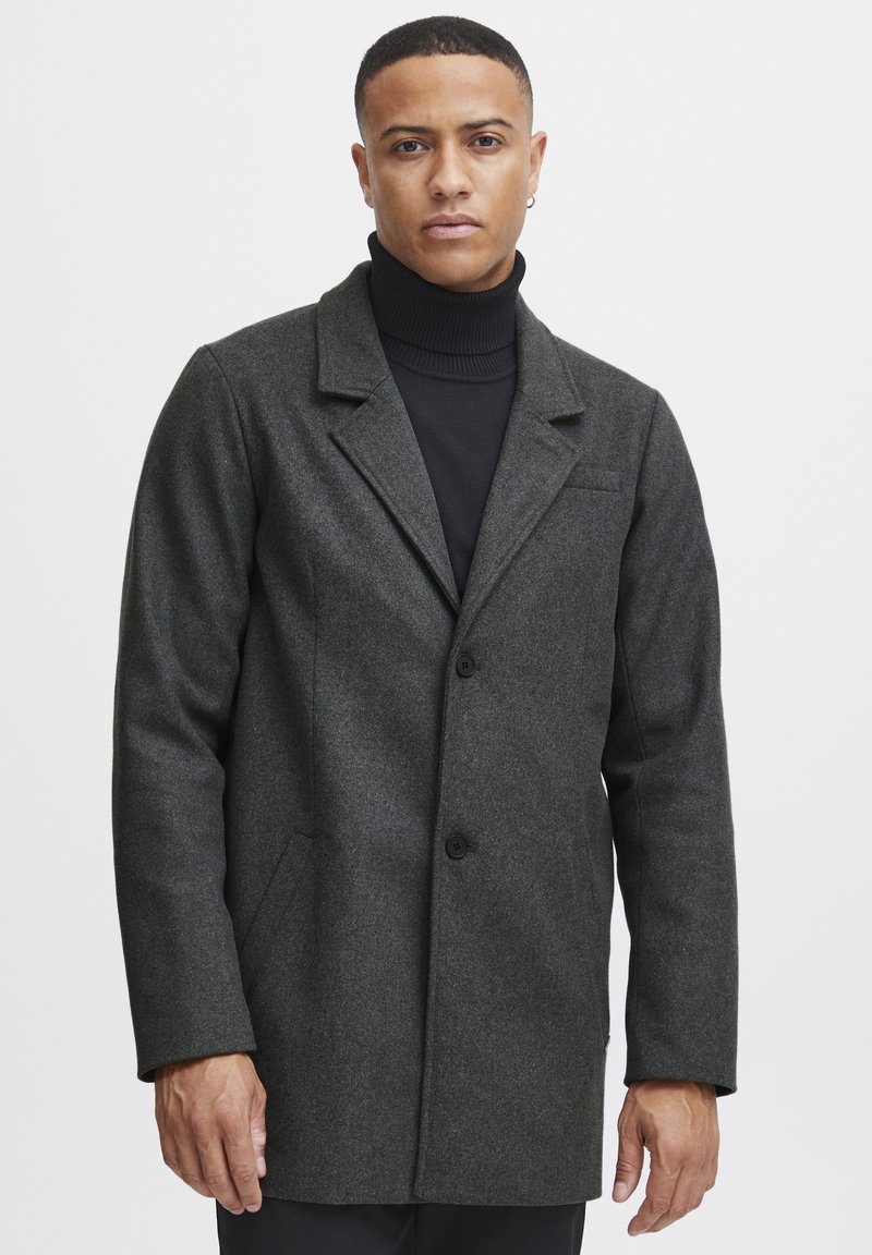 Abrigo de mezcla de lana gris oscuro con cuello con muescas, dos botones y bolsillos laterales. Textura suave, corte ajustado y diseño minimalista.