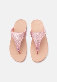 Ζευγάρι μπεζ σαγιονάρες με ροζ, λαμπερές λουρίδες, εμφανίζονται από πάνω σε απλό ανοιχτό φόντο.