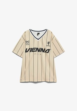 Maglietta beige a maniche corte con scollo a V, sottili righe verticali nere, scritta "VIENNA", logo di ballerina e dettaglio "EST. 1976" sul davanti.