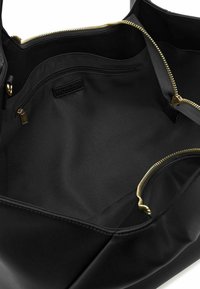 Borsa tote nera con esterno liscio, cerniere color oro e interno caratterizzato da molteplici tasche e una texture simile al raso.