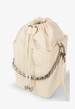 Bolso tipo cubo de cuero crema con cierre de cordón y detalle de correa de cadena geométrica plateada.