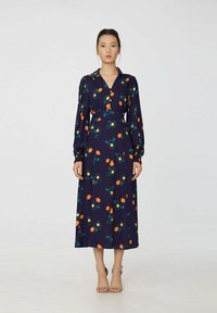 Robe de marine avec un motif floral en orange et vert. Comprend des manches longues, un col et une taille cintrée, tombant jusqu'au mollet.