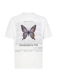 Weißes Baumwoll-T-Shirt mit kurzen Ärmeln, das ein großes lila und schwarzes Schmetterlings-Graphic zeigt und den Text "KOMPASSION" im Hintergrund wiederholt.