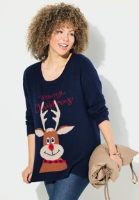 Mörkblå tröja med renmönster, plyschstickad tyg, rundad halsringning och texten "God Jul" i röd ovanför motivet.