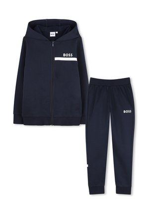 Ensemble sweat à capuche bleu marine et pantalon assorti avec logo blanc "BOSS" sur la poitrine et la cuisse, fermeture éclair avant sur le sweat, poignets côtelés aux manches et aux pantalons.