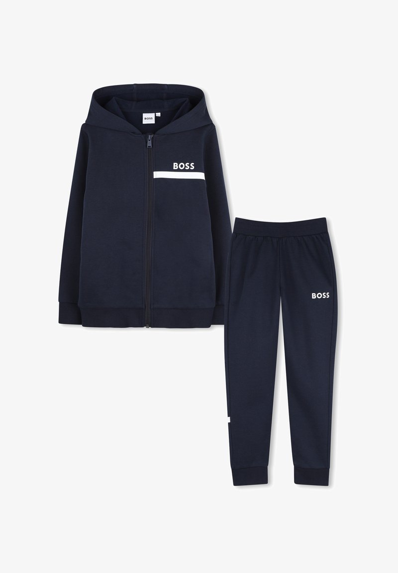 Ensemble sweat à capuche bleu marine et pantalon assorti avec logo blanc "BOSS" sur la poitrine et la cuisse, fermeture éclair avant sur le sweat, poignets côtelés aux manches et aux pantalons.