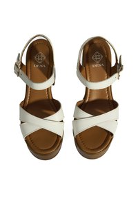 Sandales en cuir blanc avec un design à lanières croisées, semelle intérieure rembourrée marron et fermeture à boucle. Semelle plateforme marron légèrement surélevée.