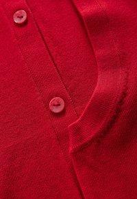Rode gebreide cardigan met een ronde kraag en een enkele knoopsluiting. Zachte textuur met fijne ribbeldetails bij de zoom.