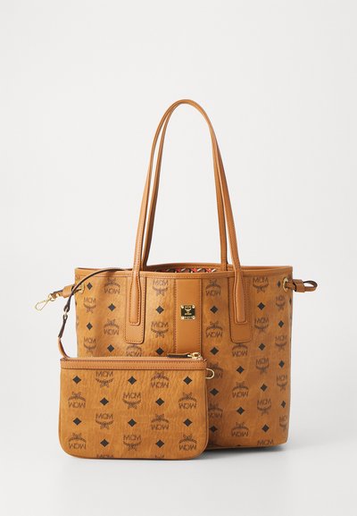 Bruine leren MCM-tote tas met zwarte logo-patronen en een bijpassende afneembare pouch met rits en polsband.