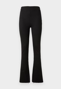 Black flared leggings made of stretchy fabric with a high waistband. Features a seamless design and side zippers at the hem.