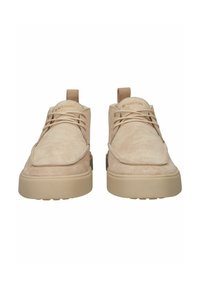 Scarpe in suede beige con punta arrotondata, suole piatte e dettagli cuciti. Presentano lacci e una linguetta sul retro per una facile calzata.