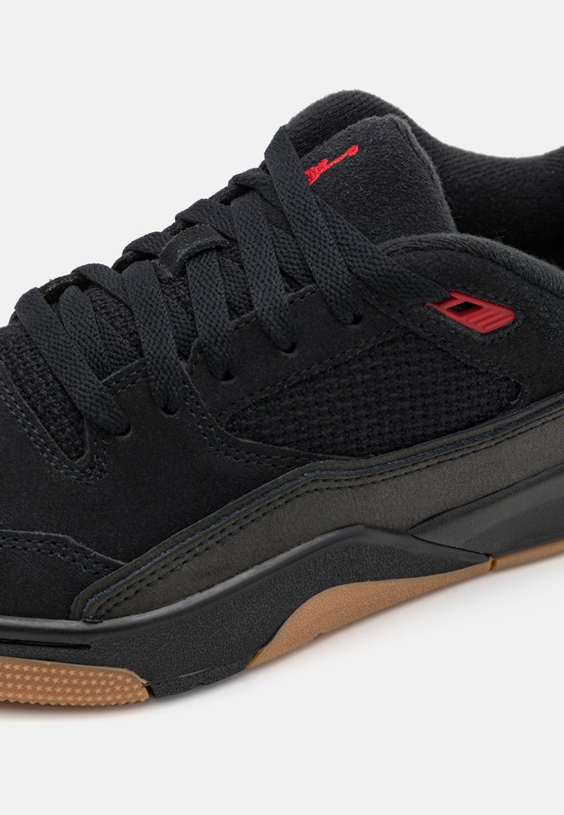 Czarne sneakersy z cholewką z zamszu i siateczki, teksturowanym czarnym wykończeniem, czerwonymi akcentami i brązową gumową podeszwą.