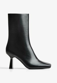 Cizmă neagră din piele până la gleznă cu vârf pătrat, având un toc bloc subțire. Suprafața este netedă, cu un finisaj lustruit.