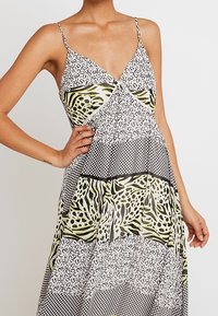 Maxiklänning med tunna axelband, med en blandning av svart, vitt och gröna mönster inklusive djurprint och rutor, i lätt tyg.