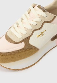 Αθλητικό παπούτσι με ροζ, μπεζ και λευκά υλικά, με υφή ψευδοδερμάτινου σχεδίου. Διακοσμημένο με στρογγυλά κορδόνια και λογότυπο σε χρυσό χρώμα.