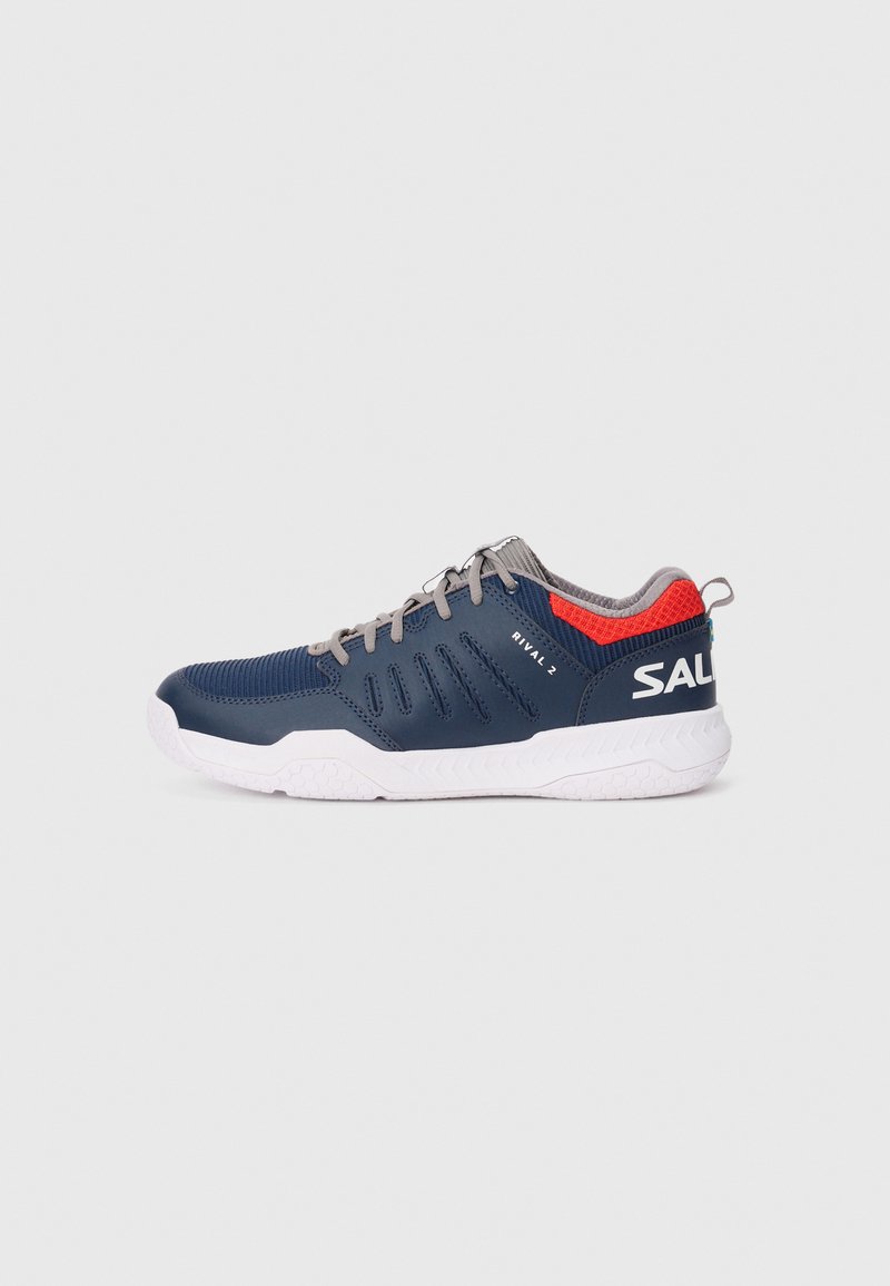 Baskets d'athlétisme marines avec une tige texturée, des lacets gris, un accent rouge au niveau du talon et une semelle en caoutchouc blanc dotée d'un motif de traction.