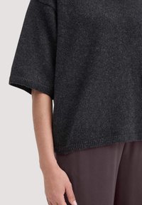 Maglione lavorato a maglia di un grigio scuro con maniche corte, una vestibilità comoda e dettagli a coste sul fondo. Texture liscia, design minimalista, adatto per sovrapposizioni.
