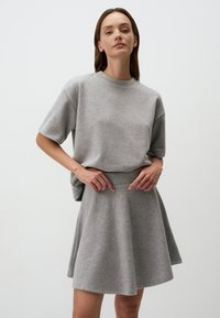 Grijze gebreide top met korte mouwen, gecombineerd met een bijpassende zwierige rok. Gladde textuur, ontspannen pasvorm en een eenvoudig ontwerp zonder patronen of accenten.