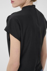 Blouse noire à manches courtes avec un col haut et une fermeture à boutons au dos. Texture douce avec de légers fronces aux épaules et une coupe décontractée.