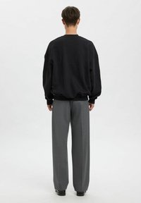 Czarna, oversize'owa bluza z prążkowanym dołem i mankietami, zestawiona z szarymi, szerokimi spodniami w delikatną kratę.