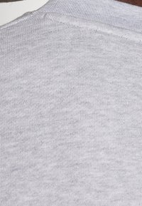 Tessuto di cotone grigio che mostra una superficie testurizzata. La vista ravvicinata mette in evidenza la maglia morbida e i dettagli delle cuciture lungo il colletto.