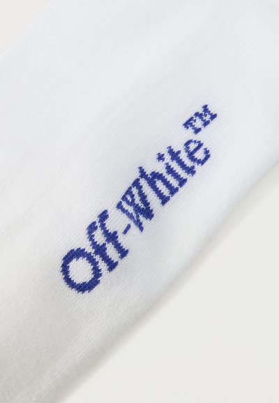 Tissu blanc présentant le nom de la marque "Off-White" tissé en bleu ainsi que le symbole de la marque déposée sur une surface texturée.