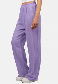 Lichtpaarse, relaxte broek van textuurstof met een elastische tailleband. Gestyled met witte schoenen.