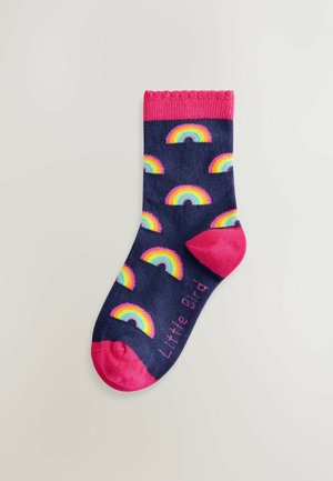 Marine sok met een herhalend regenboogpatroon, roze geribde boord en teen, met de tekst "Little Bird" in het roze aan de zijkant.