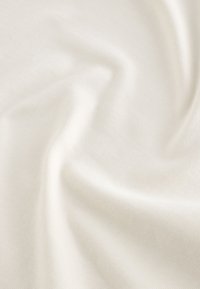 Cream colored fabric with a soft, textured surface, showcasing subtle weave patterns and gentle draping folds.