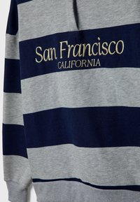 Grijze en marineblauwe gestreepte polo met "San Francisco CALIFORNIA" in het goud geborduurd. Textiel van gestructureerde katoen met een kraag.