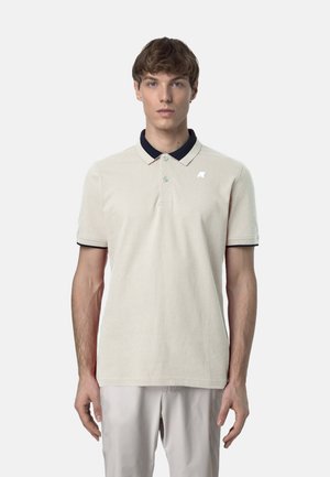 Polo shirt beige chiaro con colletto navy, maniche corte e una texture sottile. Presenta un piccolo logo sul petto e bottoni sul collo.