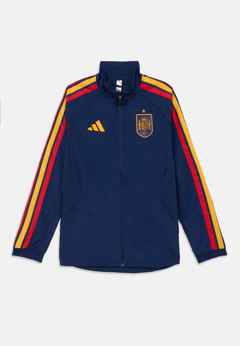 Námořnicky modrá sportovní bunda s červenými a žlutými pruhy na rukávech, předním zipem, logem Adidas a znakem španělského národního fotbalového týmu na hrudi.