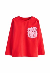 Chemise rouge à manches longues, avec une coupe ample, présentant des lettres bulle roses avec l'inscription "SOUL SHINE" sur le haut à gauche de la poitrine.
