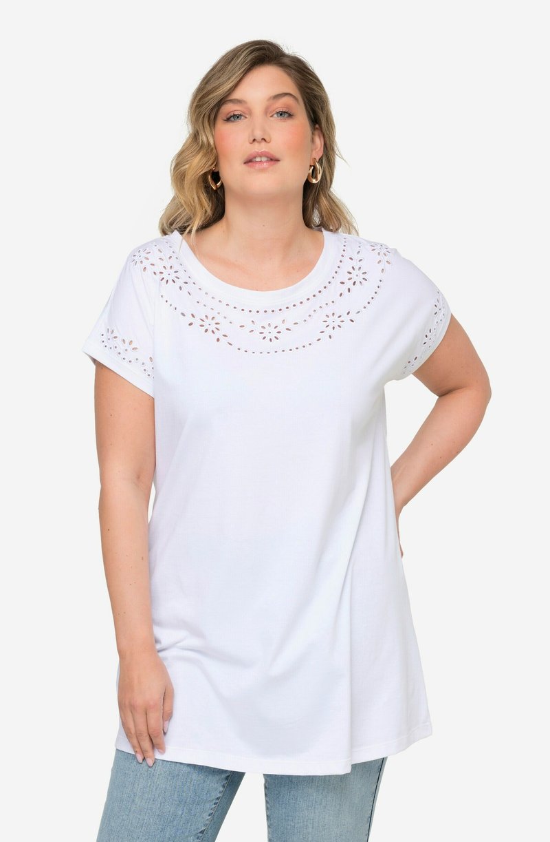 Camiseta blanca de algodón con mangas cortas, presenta detalles de ojales en el escote, corte relajado y longitud hasta la cadera.