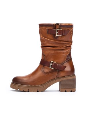 Brown leather ankle boot with scrunched design, adjustable buckle straps, and a chunky, textured heel. Rubber sole with traction grooves.