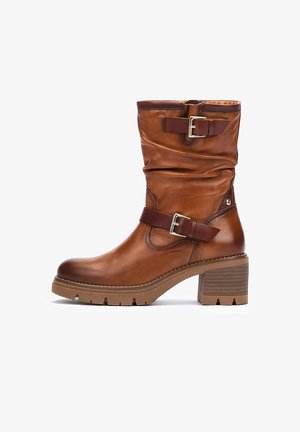 Brown leather ankle boot with scrunched design, adjustable buckle straps, and a chunky, textured heel. Rubber sole with traction grooves.