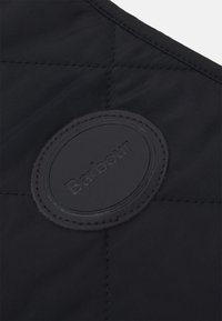 Μαύρο καπιτονέ ύφασμα με έναν γύρο ανάγλυφο μαύρο δερμάτινο μπατζάκι που φέρει το όνομα της μάρκας "Barbour" στο κέντρο. Διακριτική υφή ραφής.