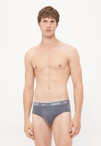 Graue Nike-Unterwäsche mit einem kontrastierenden Bund, der den Markennamen trägt. Der Stoff wirkt weich und hat eine schmale Passform.