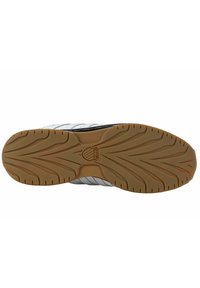 Shoe outsole with a gum rubber tread, featuring a zigzag pattern and a central logo. The upper has grey accents with white stripes.